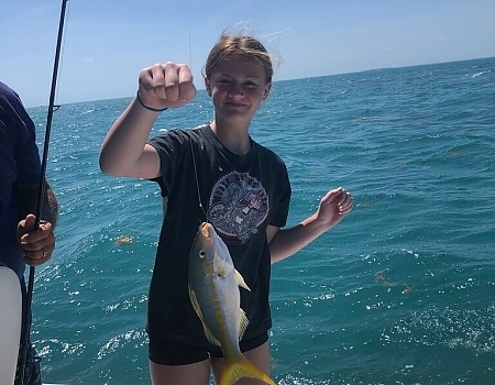 Girl holding a fish on a boat in Key Largo during a family fishing trip.