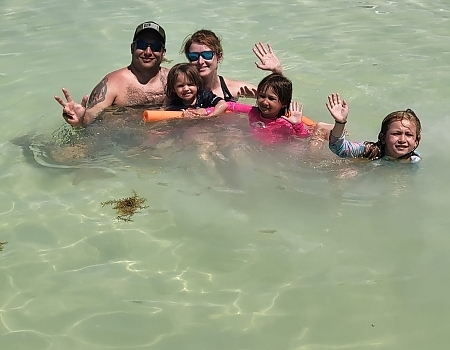 Family of five in shallow water waving during an Islamorada boat tour.