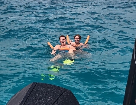 Two people floating on pool noodles in the ocean during a Key Largo boat tour.