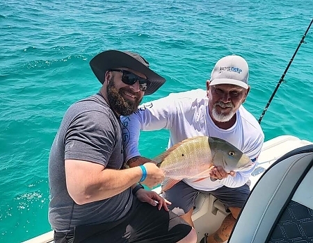 Two men holding a fish on a boat in Key Largo with Beyond Blessed Charters.