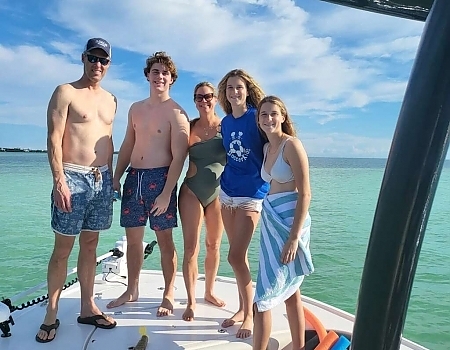 Family of five standing on a boat in shallow water during a sandbar adventure in Islamorada.