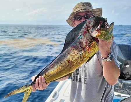 Man holding a large fish on a boat during a Key Largo fishing charters trip.