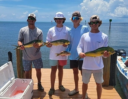 Four men holding fish on a dock after inshore fishing in Islamorada.