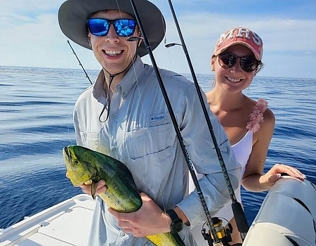 Man holding a fish with a woman smiling beside him on a boat in Islamorada.