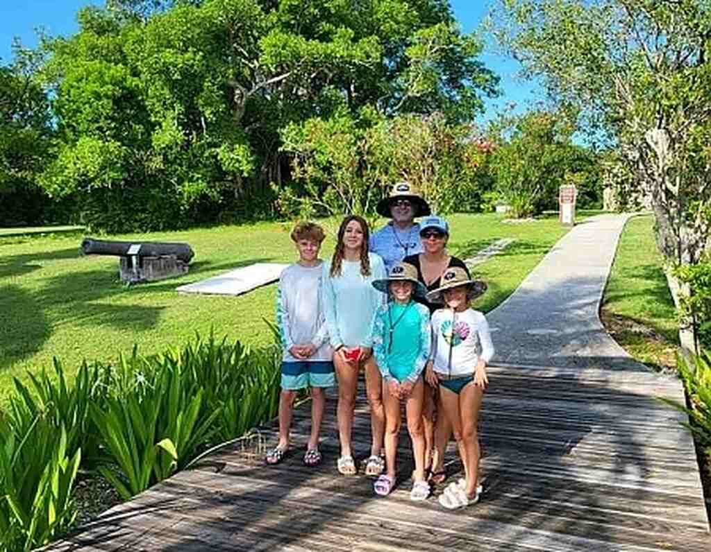 Family posing on a boardwalk with greenery and a cannon in the background in Key Largo.