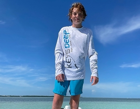 Boy standing on a boat in shallow water in Key Largo.
