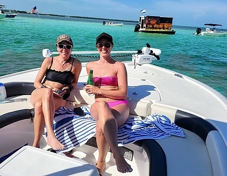 Two women relaxing on a boat with a floating bar in the background in Key Largo.