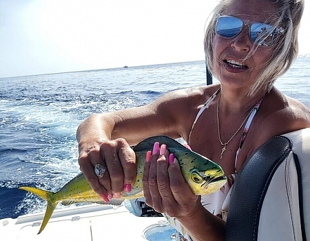 Woman holding a small fish on a boat in Key Largo with Beyond Blessed Charters.