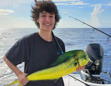 Young man holding a fish on a boat during Key Largo fishing charters.
